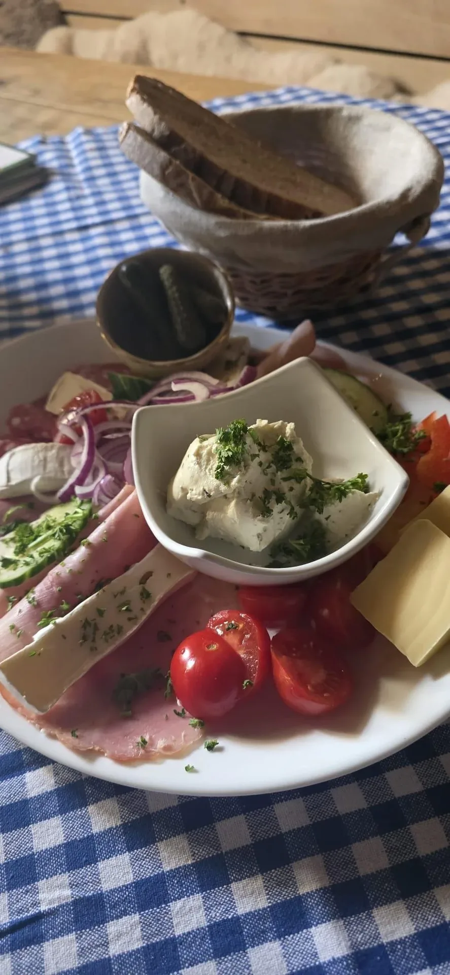 Brotzeitplatte mit Käse, Gurken und Tomaten.