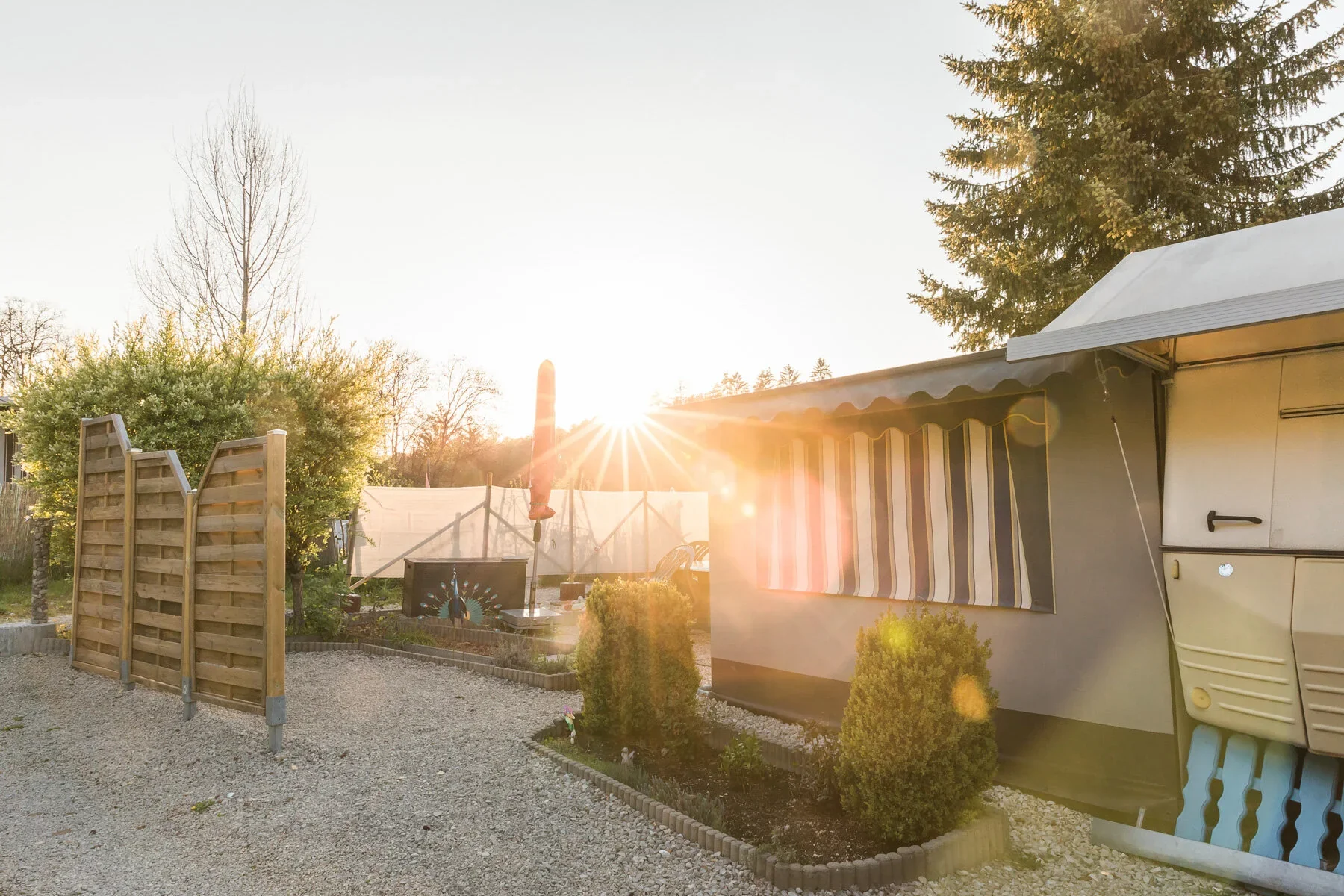 Wohnwagen und Terrasse bei tief stehender Sonne.