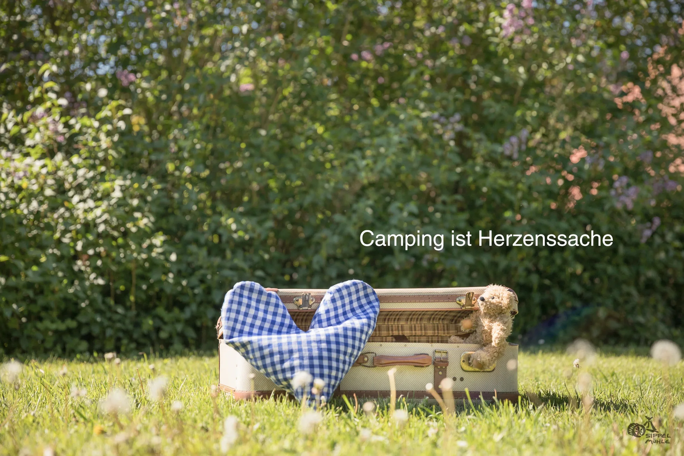 Holzbank und blaues Stoffherz mit dem Schriftzug: Camping ist Herzenssache.