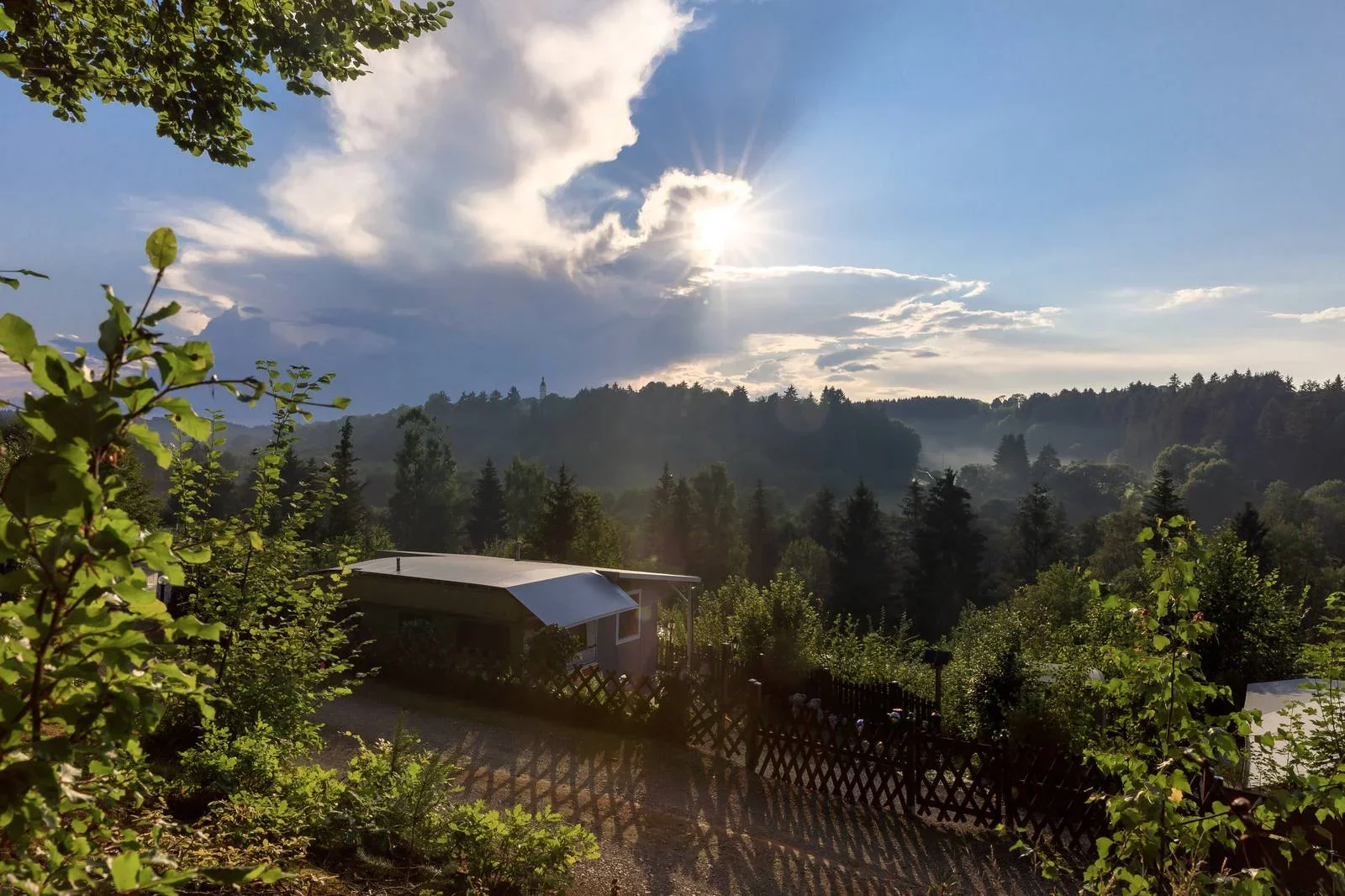 Sonnenstrahlen brechen durch Wolken über einem Dauerstellplatz.