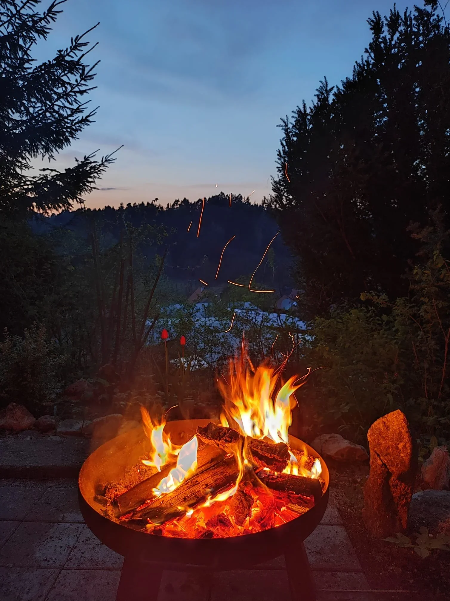 Feuerschale in der Abenddämmerung vor einem Wohnwagen.
