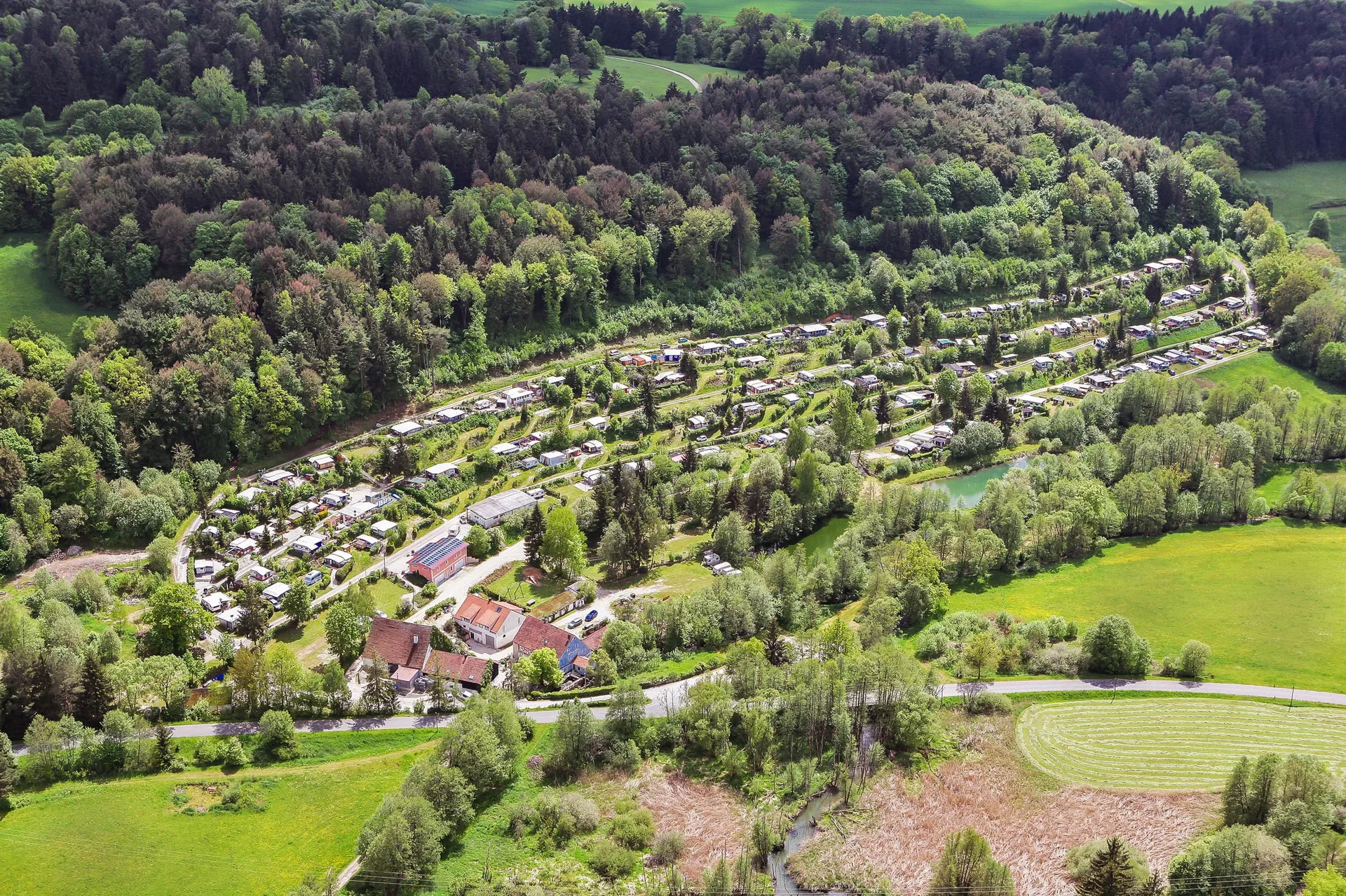 Luftaufnahme des Campingplatzes Sippelmühle in einer grünen Wald- und Wiesenlandschaft.
