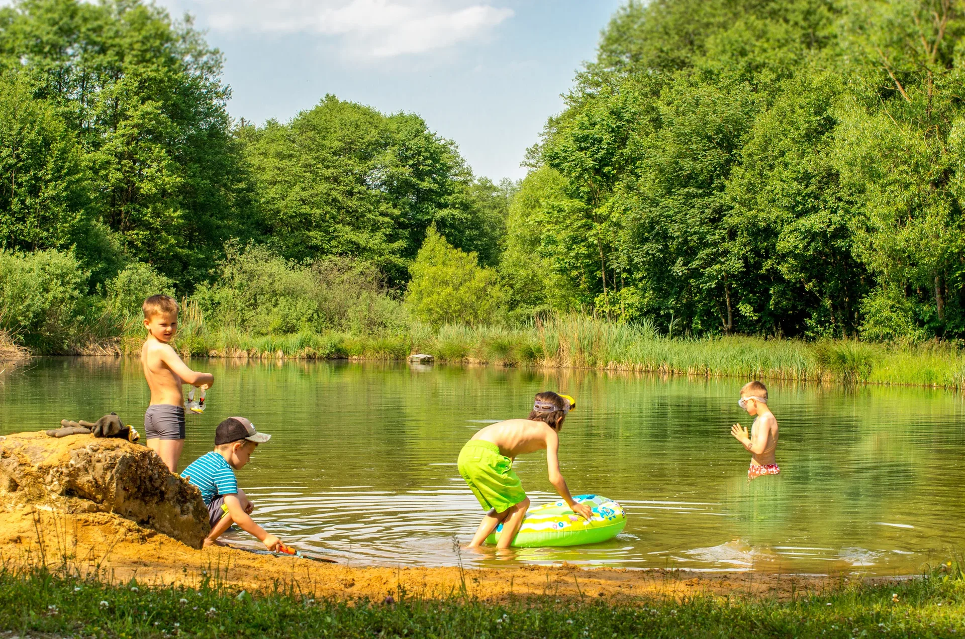 Kinder spielen am Ufer des Weiher mit Badestelles.