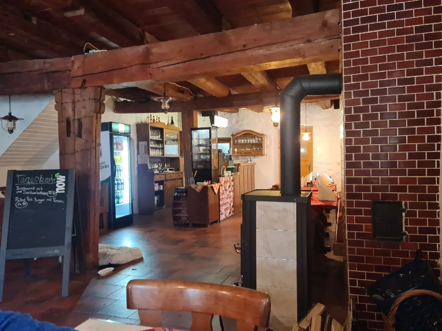 Gastraum des Landgasthofs mit Ofen und Theke.