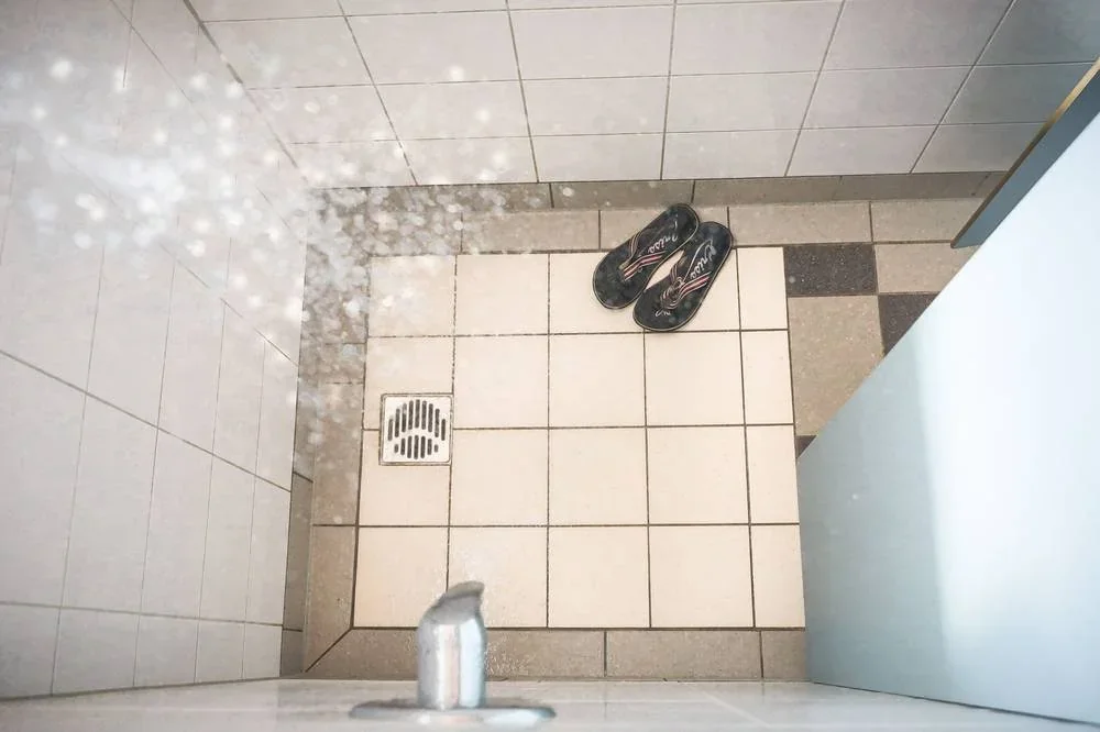 Blick in die geflieste Dusche mit Wasserstrahl.