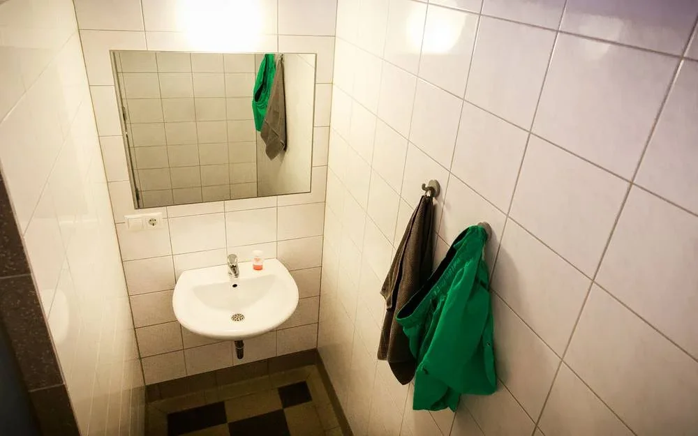 Separate Waschkabine mit Waschbecken, Spiegel und Handtuchhaken.