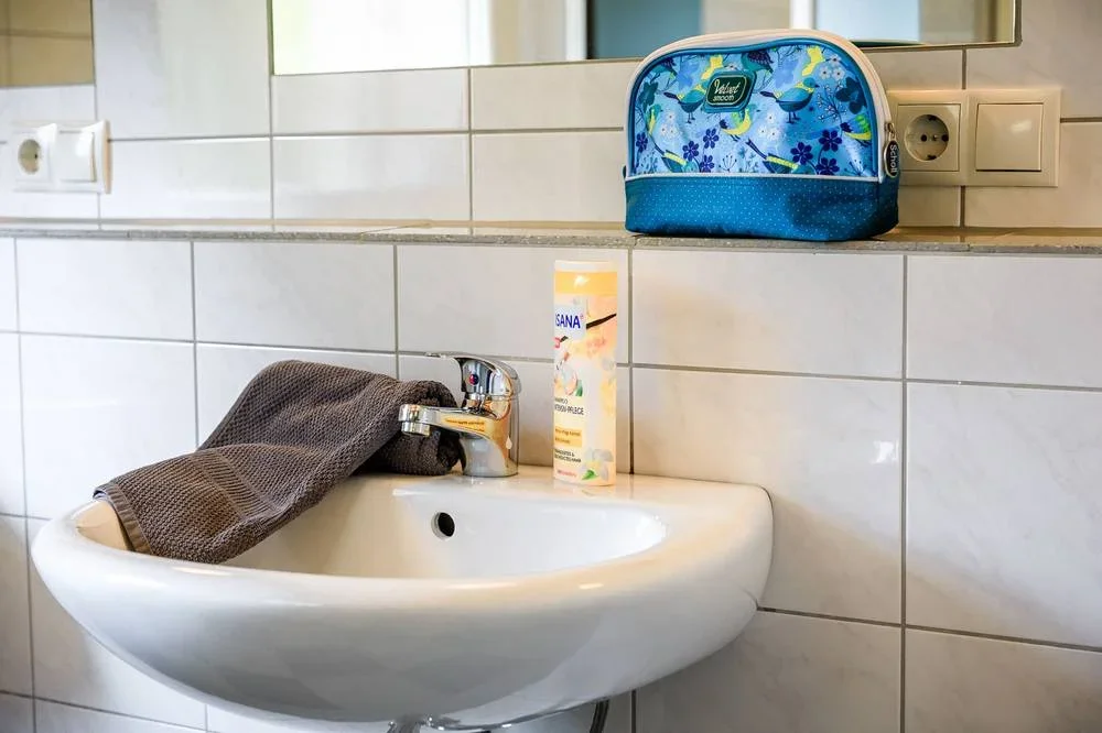 Waschbecken mit Spiegel, Ablage und gefaltetem Handtuch.