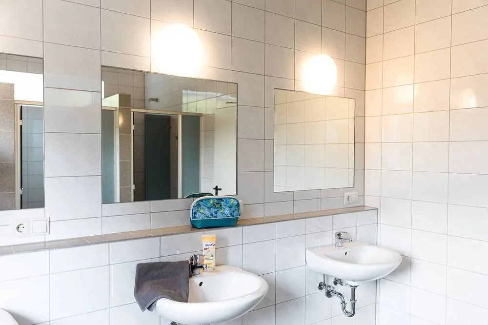 Gemeinschaftlicher Waschbereich mit mehreren Waschbecken und Spiegeln.