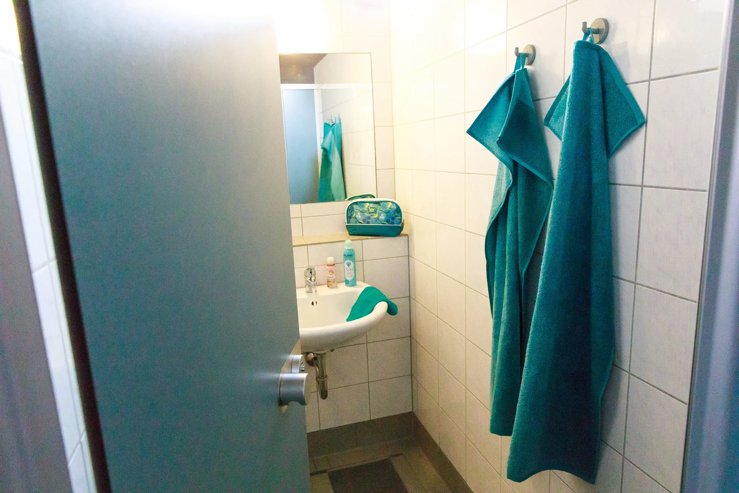 Blick durch die geöffnete Tür in eine Einzelwaschkabine.