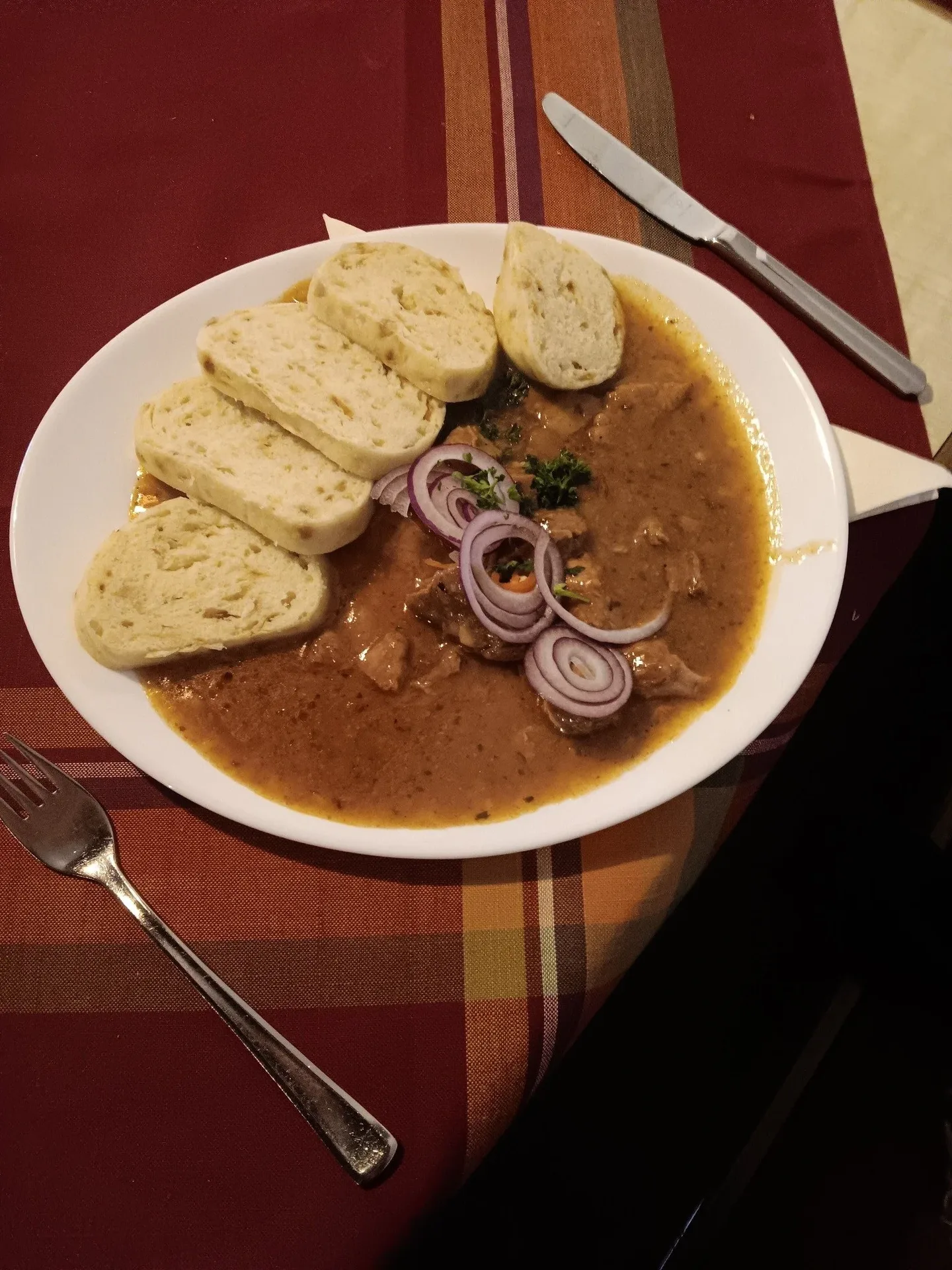 Teller mit Schweinegulasch und Semmelknödeln.
