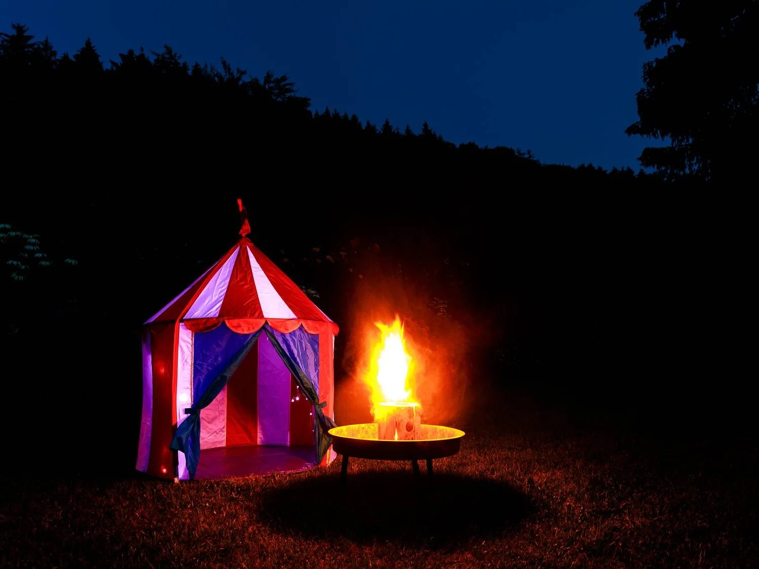 Beleuchtetes Zelt und Lagerfeuer am Abend.