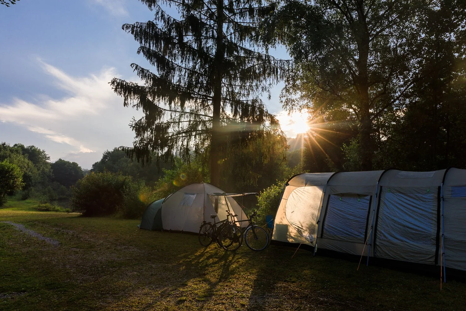 Abendsonne zwischen Zelten und Bäumen.