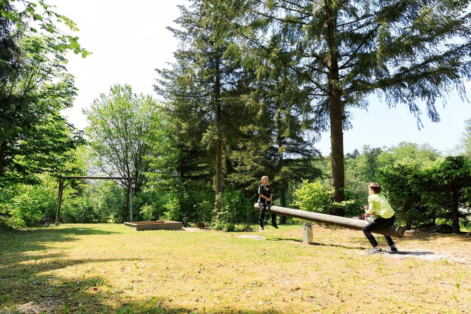 Kinder spielen auf der Wippe im Grünen.