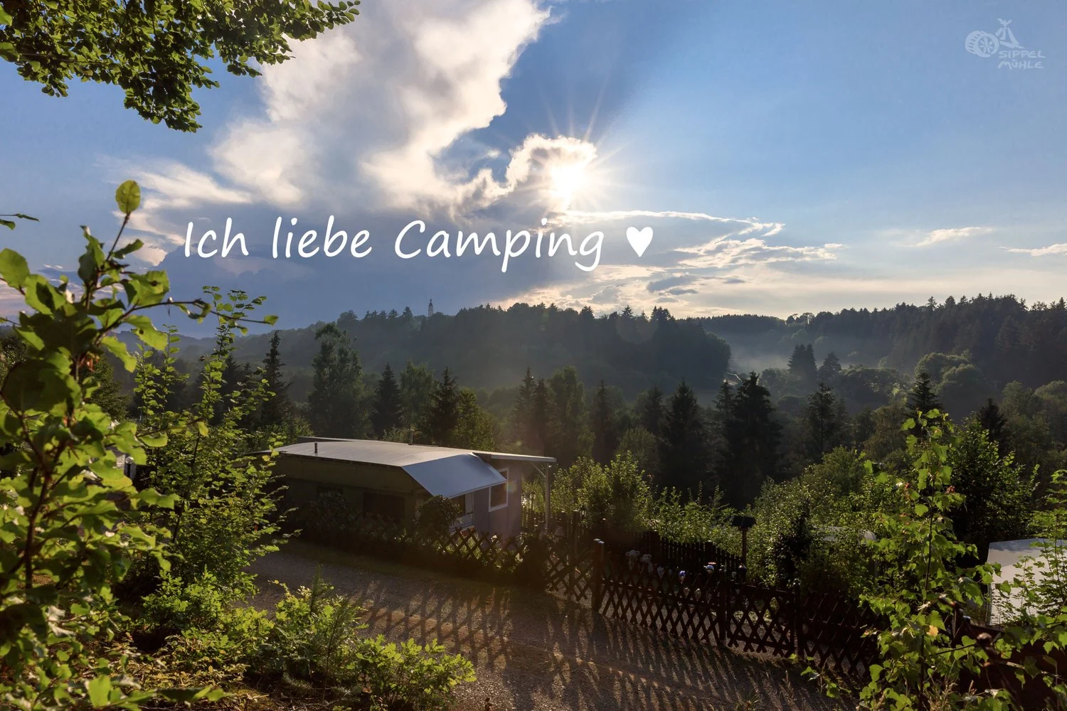 Blick über das Tal im Abendlicht mit dem Schriftzug: Ich liebe Camping.