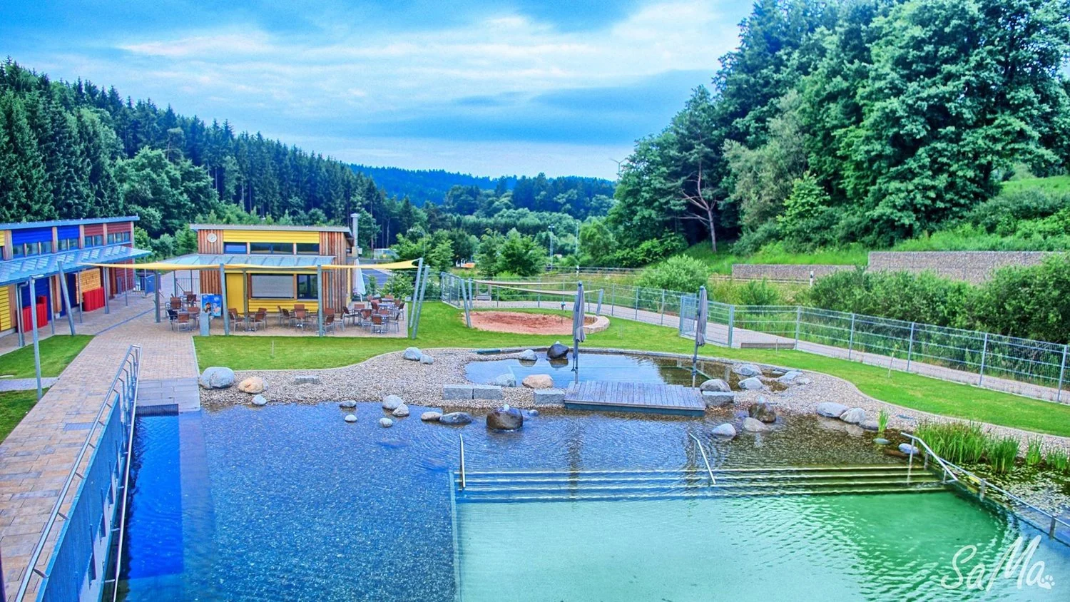 Naturbad Deining mit Schwimmbecken und grüner Umgebung.