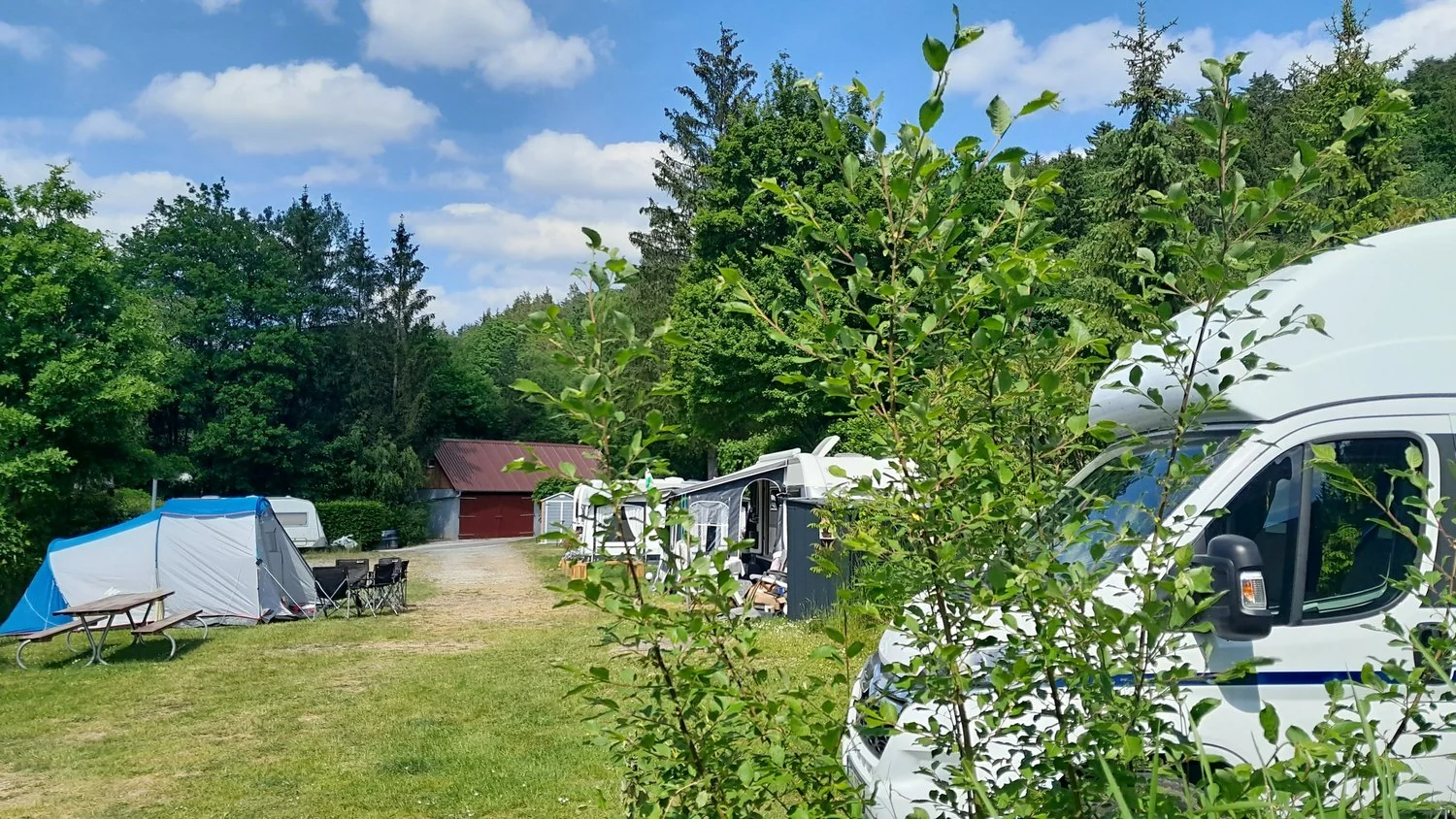 Zelte und Wohnmobile auf dem begrünten Campingplatz.