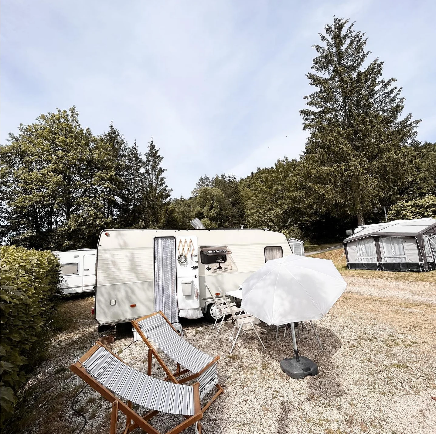 Wintercamping mit Wohnwagen und verschneiter Sitzgruppe.