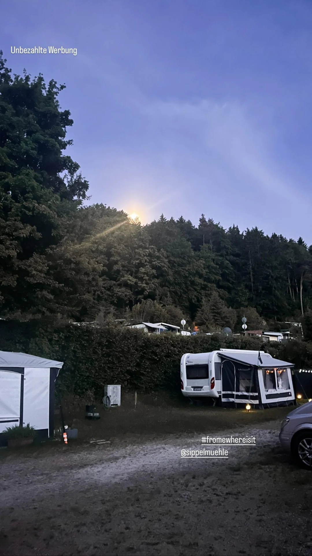 Wohnmobile unter einem dunklen Abendhimmel.