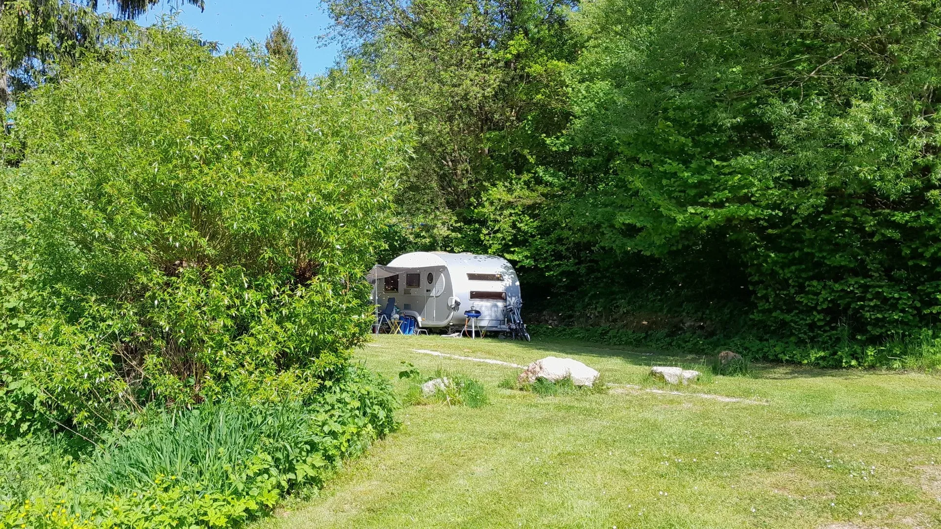 Wohnwagen auf einem begrünten Urlaubsstellplatz.