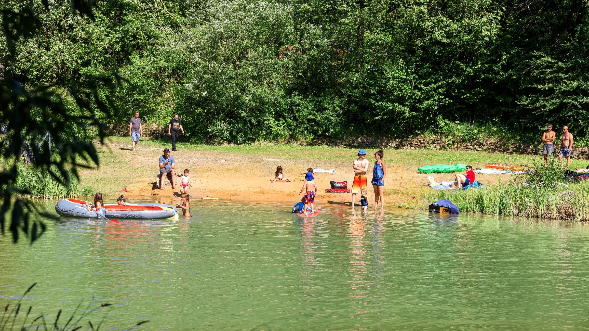 Menschen beim Baden am Weiher mit Badestelle.