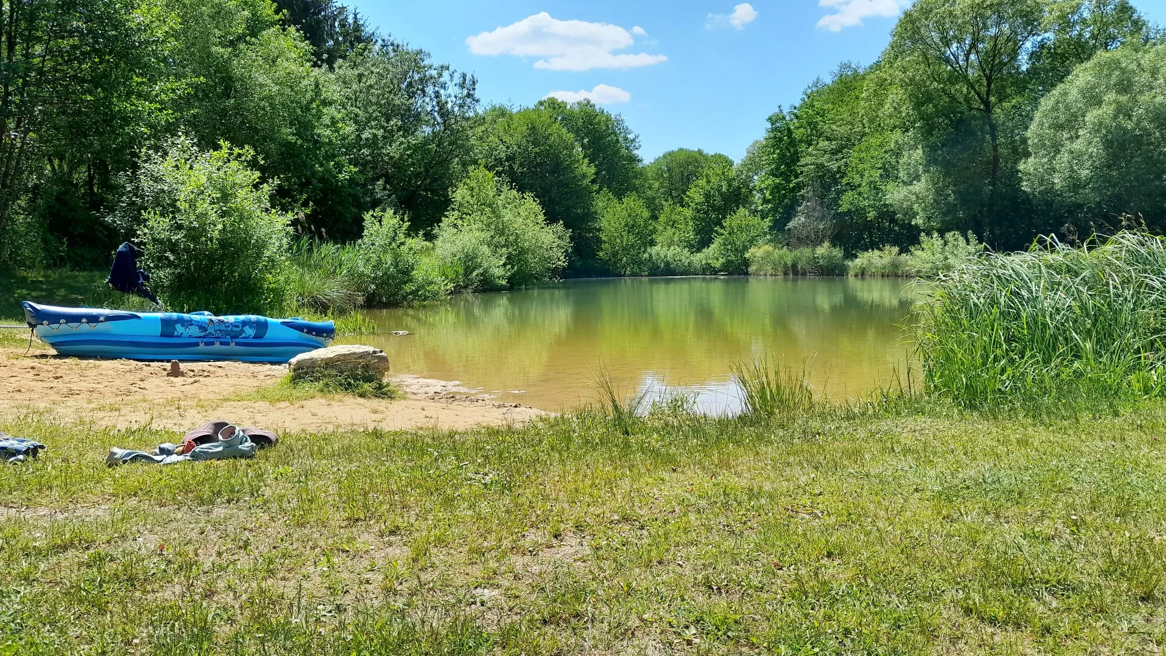 Ruhiges Ufer des Weiher mit Badestelles mit Bäumen.
